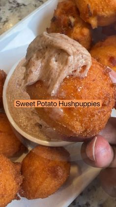 a person dipping something into a bowl filled with doughnuts on top of a white plate