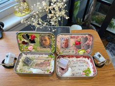 three tins filled with different types of items on top of a wooden table next to a window