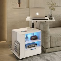 a laptop computer sitting on top of a white shelf next to a couch in a living room