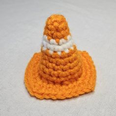 an orange and white crocheted hat sitting on top of a white tablecloth