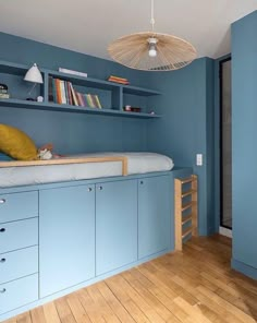 a bedroom with blue walls and built in bookshelves on the wall, along with wooden flooring