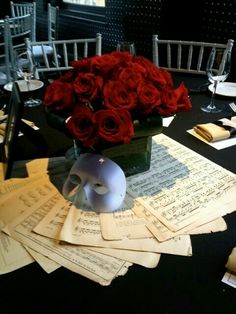 a table topped with lots of sheet music and red roses