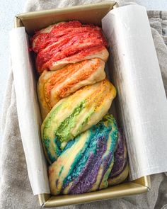 a box filled with different colored pastries on top of a table next to a towel