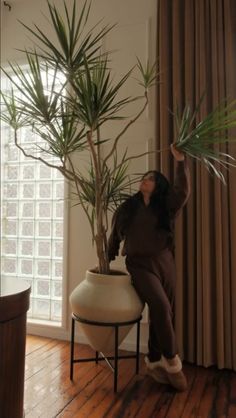 a woman is sitting on a chair with a plant in her hand and she is looking up at the ceiling