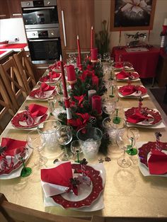 the table is set for christmas dinner with red cloths and silverware on it