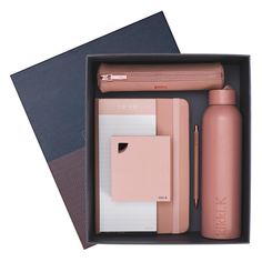 a pink bottle, notebooks and pen in a box