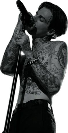 a man with tattoos on his body holding a microphone and singing into the microphone while standing in front of a white background