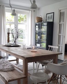 a dining room table with two chairs and a bench in front of the window that is open