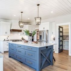 an instagramted photo of a kitchen with blue and white cabinets, wood flooring