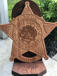 a carved wooden sheriff badge on top of a wood stand in front of some bushes