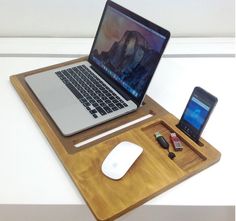 an open laptop computer sitting on top of a wooden tray next to a cell phone