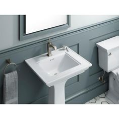 a white sink sitting next to a toilet in a bathroom under a mirror on the wall