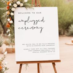 an unplugged ceremony sign with flowers and greenery is displayed on easel