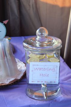 a glass jar filled with lemon slices sitting on top of a purple tablecloth covered table