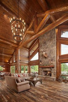 a living room filled with furniture and a fire place under a chandelier on top of a wooden ceiling