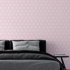 a bed sitting in front of a pink wall with white polka dots