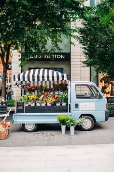 a blue truck parked in front of a flower shop