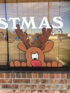 a christmas window with a reindeer drawn on it's face and the words stmas written in white