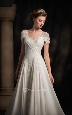 a woman in a white wedding dress standing against a black background wearing a tiara