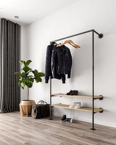 an open closet with clothes and shoes hanging on the wall, next to a potted plant