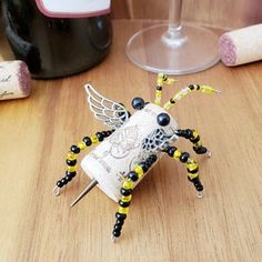 a wine glass holder with a bee on it sitting next to a bottle and corkscrews