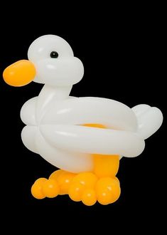 an inflatable white duck sitting on top of yellow balls with black back ground