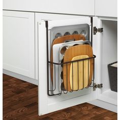 an open cabinet with dishes and cutting boards in the bottom drawer, on top of a wooden floor