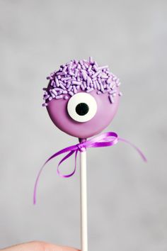 a purple cake pops with sprinkles on it and an eyeball in the middle