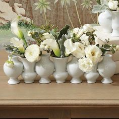 white vases with flowers in them sitting on a table