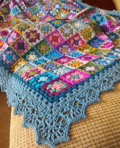 a crocheted blanket sitting on top of a couch next to a wooden chair