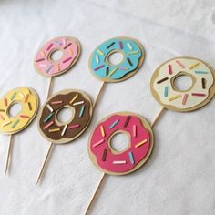 six donuts on sticks with sprinkles are arranged in the shape of doughnuts