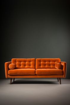 an orange couch sitting on top of a gray floor next to a black wall in a room