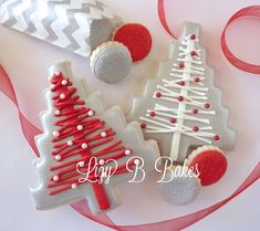 three decorated christmas cookies sitting on top of a table next to red and white ribbons