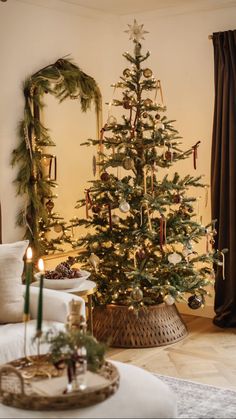 a decorated christmas tree in a living room with candles on the table and other decorations