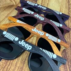 four pairs of jeep sunglasses on top of a wooden table with the words jeep printed on them