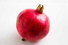 a red pomegranate sitting on top of a white table