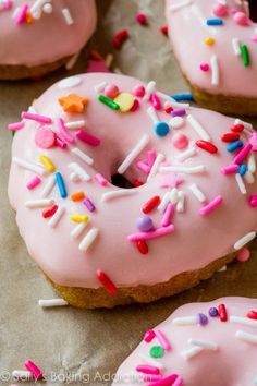 pink frosted doughnuts with sprinkles and colored icing on parchment paper