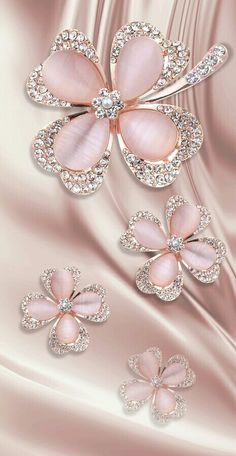 three flower brooches on a satin background with diamonds in the center and four petals attached to them