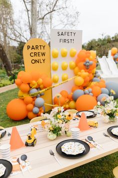 an outdoor party is set up with orange and gray decorations, plates and napkins