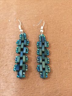 two pairs of blue beaded earrings sitting on top of a table