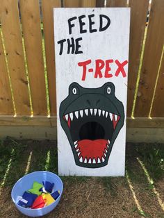 a sign that says feed the t - rex next to a bowl of toys