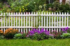 a white picket fence surrounded by colorful flowers