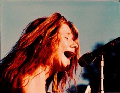 a woman with long hair singing into a microphone