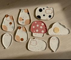 nine ceramic dishes with designs on them sitting on a wooden table next to each other