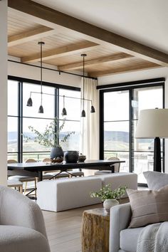 a living room filled with furniture and lots of large windows next to a dining table