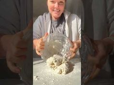 a woman holding a glass bowl filled with white powdered food and smiling at the camera