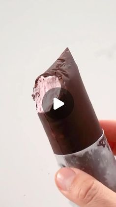 a person holding a piece of chocolate with pink frosting