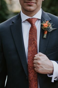 a man wearing a suit and tie with an orange boutonniere on his lapel