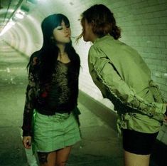 two young women standing next to each other in a subway tunnel, one with her mouth open