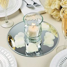 there is a candle that is on the table with plates and silverware in front of it